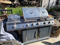Front angle view of full grill showing dual lids, control knobs and lower cabinet