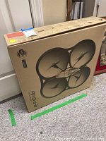 Photo of original Parrot AR Drone cardboard box showing large graphic of drone, WiFi and Bluetooth logos.