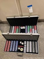 Two open cases of poker chips showing multiple colored chips stacked, dealer buttons, red dice,and card holders