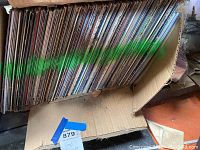 Side angle view of the box holding a large number of vinyl records upright showing the spines/sleeves with wear and aged condition.