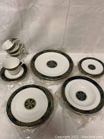 Group view of dinner plates, luncheon plates, soup bowls, dessert plates, teacups and saucers on white cloth backdrop