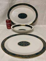 View of large oval platter, medium shallow service bowl, and medium oval platter with a soda can for size reference, showing teal and gold Carlyle pattern on white bone china.