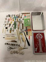 Overall lot showing multiple sewing-related items including thimbles, needles, scissors, thread spools, buttons, and two tin containers.