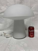 Front view of white frosted glass mushroom lamp with power cord and inline switch, scale shown by soda can
