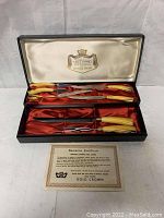 Vintage Gold Crown Sheffield stainless steel carving set with yellow handles displayed in original black box lined with cream and red satin fabric. Guarantee certificate placed in front.