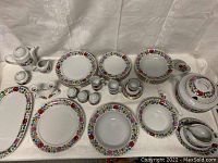 Overview of entire lot showing plates, bowls, cups and serving pieces arranged on table.