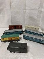 Overview of seven vintage Lionel train cars arranged on fabric background.