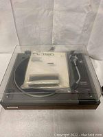 View of the Pioneer PL-112D turntable with dust cover closed, showing wood grain base and controls.