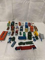Wide view of all 26 diecast toy vehicles arranged on white cloth