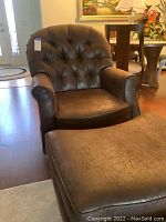 Arm chair and ottoman in brown suede cloth fabric, tufted back on chair, visible rolled arms and wooden legs.
