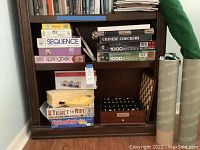 Shelf with assorted board games, puzzles, and wooden chess case