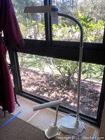 Desk and floor lamps positioned by a window showing the full view of both lamps including bases and necks.