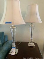 Full view of paired lamps on a wooden table next to a couch showing overall size and design.