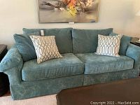 Front view of aqua textured fabric sofa with two pillows showing overall condition and style.