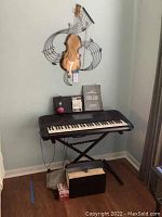 Full lot: keyboard on stand under wall art, accessories on and below keyboard