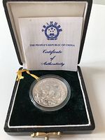 Silver 5 Yuan coin in protective capsule inside a black velvet-lined display box, certificate of authenticity behind the coin.