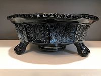 Side view of footed bowl showing three claw feet and exterior butterfly and berry panels