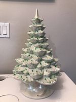 Front view of full ceramic Christmas tree with lights and base