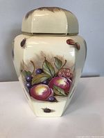 Front and partial side view of Aynsley ginger jar with hand-painted orchard fruit pattern on cream ceramic base.