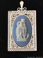 Full front view of the blue jasperware pendant with silver tone decorative frame and central classical female figure leaning on an anchor.
