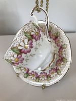 Tea cup with handle and saucer, showing floral pattern and gold trim