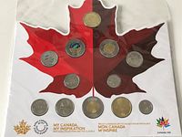 Photo showing both 2017 Canada 150th anniversary coin sets, displayed within red and dark red maple leaf shaped holders with coins secured in place.
