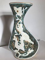 Front angled view showing textured turquoise background with white and gold raised floral and dragon motifs.