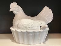 Front view of white ceramic hen tureen in basket nest base