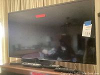 Samsung 40-inch flat-screen TV showing front view on wooden stand with label and red tape on screen.