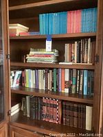 Full view of four shelves of books showing assorted titles including binders, encyclopedias, and magazines.