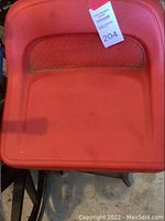 Top-down photo of the red padded seat and backrest embossed with Craftsman brand name and auction tag 204 attached