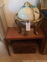 Full lot showing wooden side table with globe on top and beer crate beneath