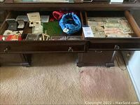Overhead view showing two open drawers containing assorted foreign currency banknotes, pins, ball bearings and other small collectible items.