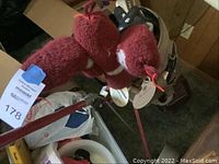 Golf clubs in brown golf bag with maroon knit animal-shaped head covers on clubs