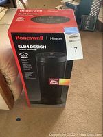 Front view of the sealed Honeywell ceramic tower heater box showing product details and branding.
