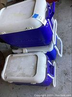 Photo of two stacked blue and white Igloo coolers and one blue and white Coleman cooler on concrete floor showing overall condition and colors.