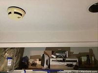 Shelf containing packed comforter, dry iron, vacuum attachment set in boxes and bags.