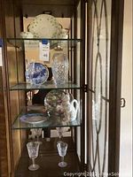 Shelved display with decorative plates, crystal vase, and glassware