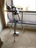 Full assembled telescope on tripod viewed from front, showing tube, tripod and number tag.