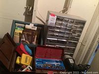 Photo showing multi-drawer organizer, several tool cases, boxed items including Norton repair kit, and a black power tool with cord