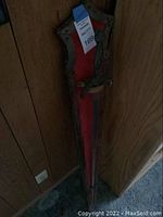 Full front view of the antique wall-mounted piece showing red center panel, metal frame, and hooks.