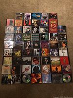 Grid of 49 CD jewel cases laid out on carpet
