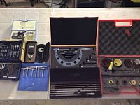 Overview of all items laid out on table, showing drill bit cases, measuring tools and hole saw kit