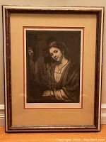 Full view of framed sepia-toned portrait of a woman with dark hair and jewelry in a beige and brown double mat and wooden frame.