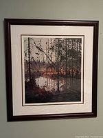 Full view of the framed artwork hung on a wall showing dark wood frame and forest landscape print.