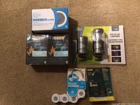 Photo showing all items together including LED lanterns, shower heads, coffee cups, surge protector, and padlock