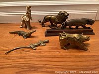 Photo showing all six brass animal figurines on wooden floor: elephant, lion, panther, crocodile, lizard, and bull.