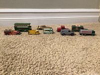 Front overview photo showing all 9 toy/model vehicles arranged in a line on carpet