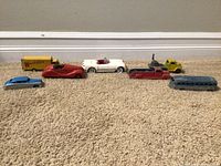 Photo of the full lot of vintage metal toy vehicles including cars and trains arranged on carpet.