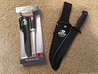 Rapala 15-inch soft grip fillet knife in original packaging next to the Mossy Oak Overswatch hunting knife with sheath on carpet floor.